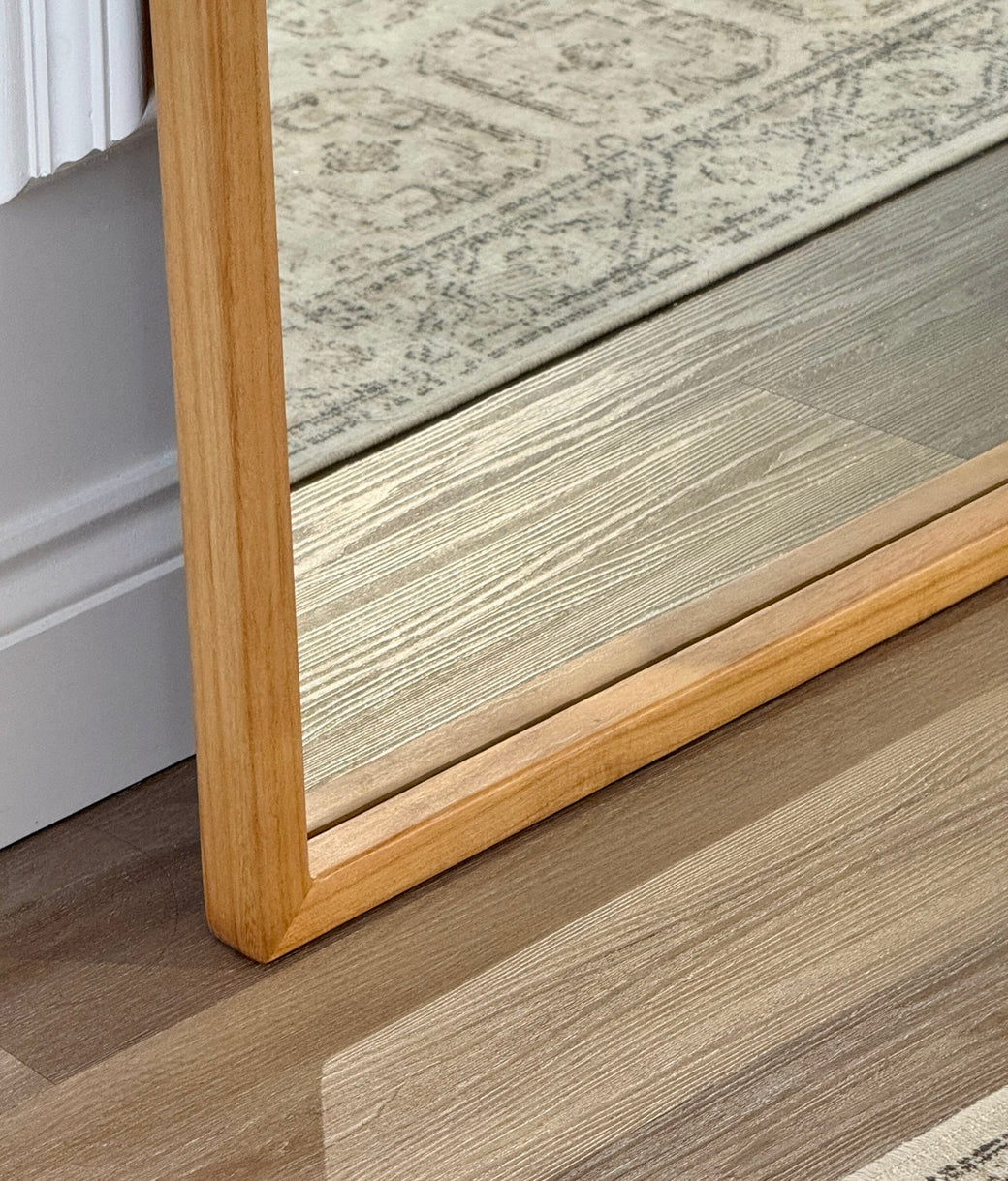 Base corner detail of natural oak wood frame on full-length leaner mirror
