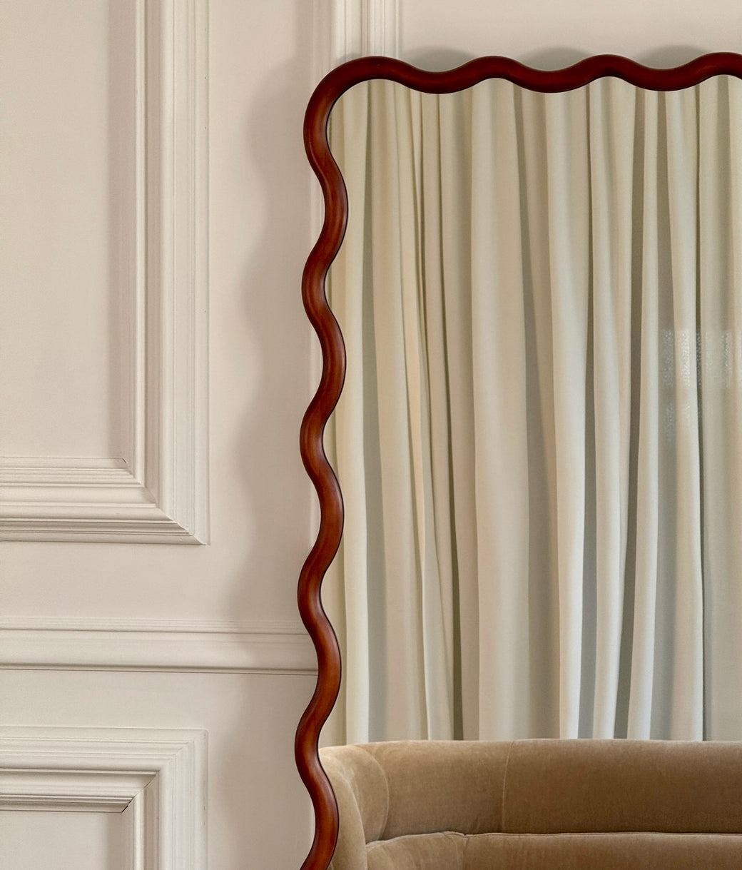 Top detail of wavy wood frame on full-length leaner mirror in walnut finish
