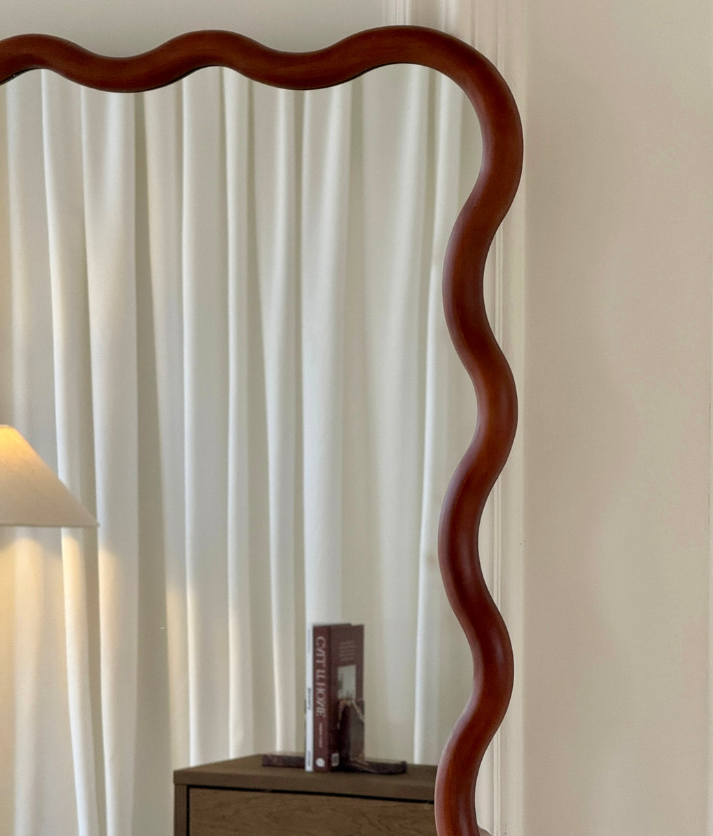 Top detail of wavy wood frame on full-length leaner mirror in walnut finish